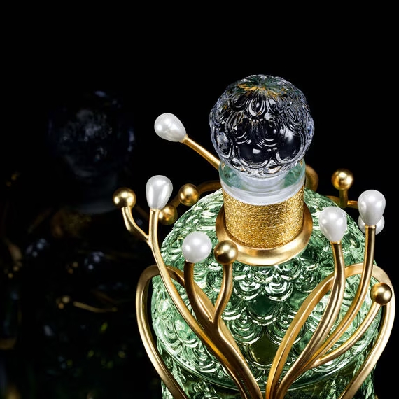 Macro of Yann Philippe’s 18 ct gold helix and pearl tips hugging the Bee Bottle, spotlighting the craft of Guerlain’s Muguet 2025 Millésime.